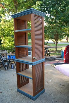 a tall wooden shelf sitting on top of a cement ground next to a park bench