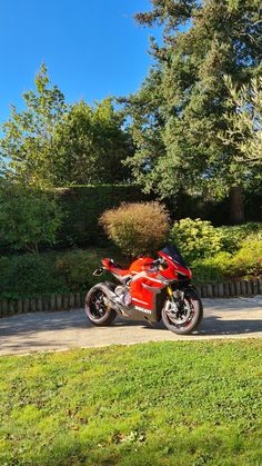 a red motorcycle parked on the side of a road next to a lush green field