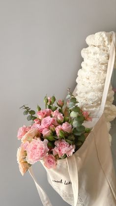 a bouquet of pink flowers in a white tote bag on top of a table