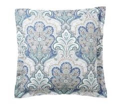 a blue and white pillow with an ornate pattern on the front, sitting against a white background