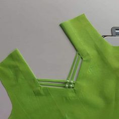 the back of a green dress being sewn on with sewing tools and thread in it