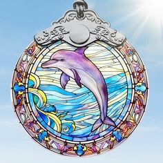 a stained glass ornament with a dolphin on it's side in front of a blue sky