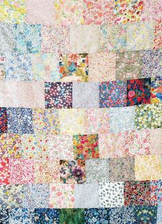 a patchwork quilt with many different colors and designs on the front, including flowers