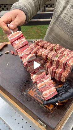 a man is cutting up raw meat on a grill