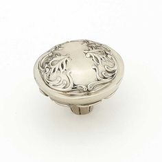 an ornate silver knob on a white background