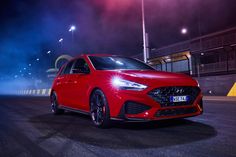 a red car driving down a street at night