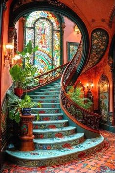 an ornate staircase with stained glass windows and potted plants on the bottom step in front of it