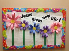 a bulletin board with paper flowers and the words jesus gives new life