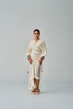 Wrap Style Blouse With Side Tie Up And Intricate Mirror And Thread Work Hand Embroidered Cuffs Materials used: Habutai Color: Ivory Product care: Dry clean only Elegant Long Sleeve Sets With Draped Sleeves, Elegant Sets With Draped Long Sleeves, Elegant Spring Kaftan With Embroidered Sleeves, Traditional Long Sleeve Cream Blouse, Festive Long Sleeve Blouse With Embroidered Cuffs, Wedding Sets With Embroidered Cuffs Long Sleeve, Cream Long Sleeve Kimono For Wedding, Elegant Long Sleeve Sets With Embroidered Cuffs, Cream Long Sleeve Blouse With Embroidered Sleeves