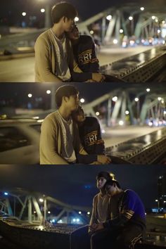 two people sitting next to each other in front of a bridge at night and one person holding his arm around the other