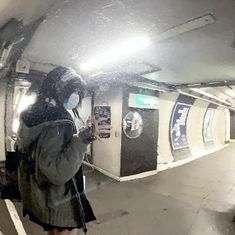 a woman wearing a face mask while standing on a subway platform