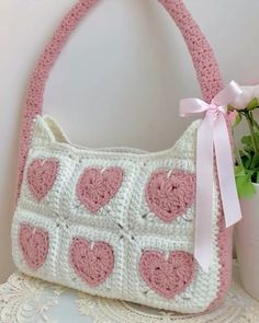 a crocheted purse with pink hearts on the front and white trimmings