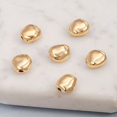 five gold - plated beads on a white marble surface