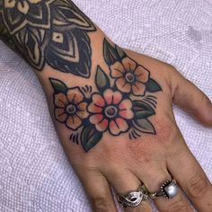 a woman's hand with flowers on it and an owl tattoo above the wrist