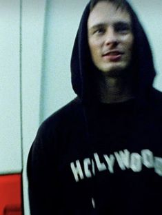 a man in a black hoodie holding a cell phone