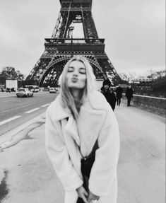 a woman standing in front of the eiffel tower with her face covered by a blanket