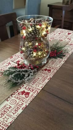 a dining room table decorated for christmas with pine cones and lights on the centerpiece