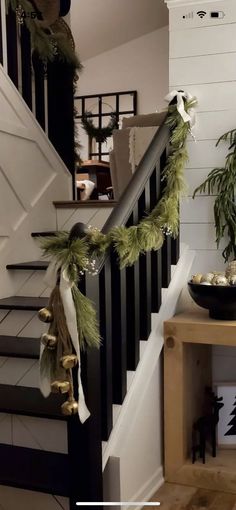 christmas garland hanging on the banister and stair railing in a home decorated with greenery