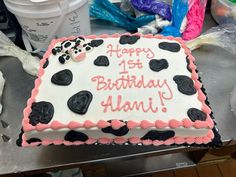 a birthday cake with pink and black frosting on it sitting on a counter top