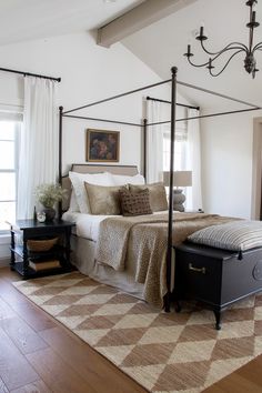 a bedroom with a four post bed, rug and chandelier in the corner