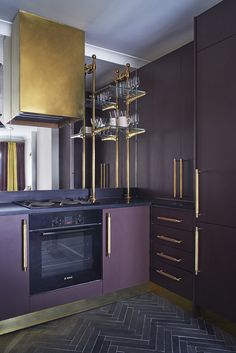 a kitchen with purple cabinets, gold accents and an oven in the middle is shown