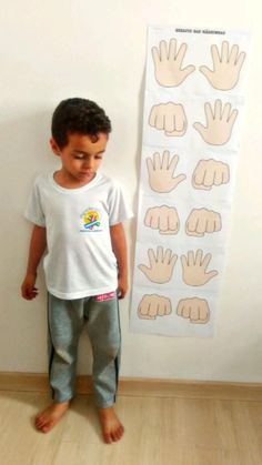 a young boy standing in front of a wall with hands on it