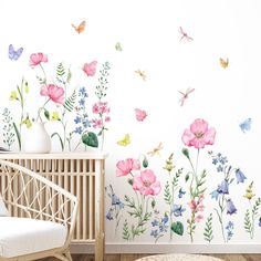 a room with flowers and butterflies painted on the wall next to a white crib