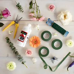 flowers and scissors laid out on a white wooden surface with the tools used to make flower arrangements