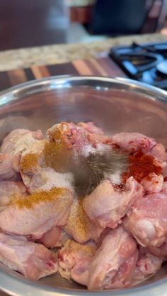 a metal bowl filled with meat on top of a counter next to a stovetop