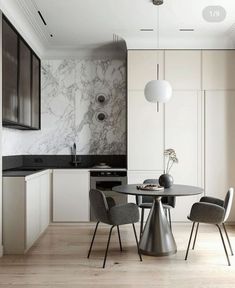 a modern kitchen with marble walls and flooring is pictured in this image, there are chairs around the table