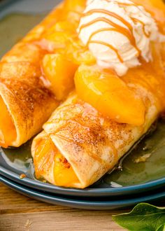 two crepes on a plate topped with whipped cream and orange slices, sitting on a wooden table