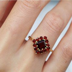 a woman's hand with a ring on it and a red stone in the middle