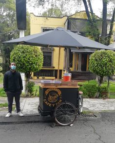 a man wearing a face mask standing next to an ice cream cart