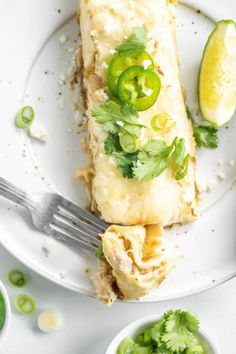 a white plate topped with food next to two small bowls filled with green peppers and limes