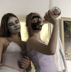 two women with facial masks holding up wine glasses