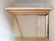 an empty room with wood floors and a ladder on the wall to reach it's door