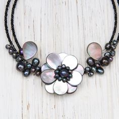 Black mother of pearl shell and peacock pearl wire-wrapped flower design Black glass seed beads Flexible/expandable memory wire, choker length Flower approximately 1.5" diameter Natural shells and pearls may vary slightly from photo Handmade in Thailand Adjustable Beaded Mother Of Pearl Necklace, Adjustable Pearl Flower Beaded Necklace, Adjustable Pearl Flower Necklace, Adjustable Mother Of Pearl Necklace With Round Beads, Handmade Adjustable Flower Pearl Necklace, Shells And Pearls, Wire Choker, Peacock Pearl, Choker Black