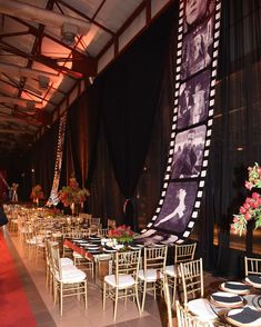 tables and chairs are set up in front of a black curtain with pictures on it