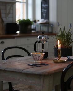 a wooden table topped with a tea pot next to a candle