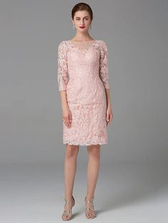 a woman wearing a pink lace dress with long sleeves and an open back, standing in front of a gray background