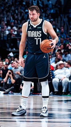 a man holding a basketball in his right hand while standing on top of a court