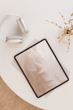 an electronic device sitting on top of a table next to headphones and a plant