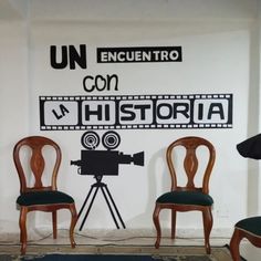 two chairs and a camera in front of a wall with the words un encuentro con historical