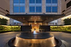 the entrance to an office building with a fountain in front of it at night time