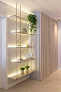 a white shelf with plants and pictures on it in front of a wall that has vertical slats