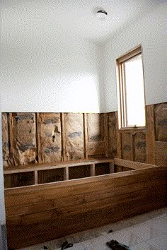 an unfinished room with wood paneling in the wall and windows on the far side