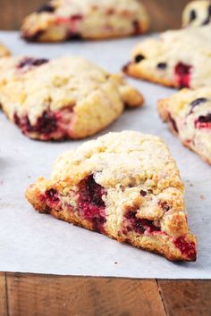 fresh blueberry scones are sitting on a piece of parchment paper and ready to be eaten