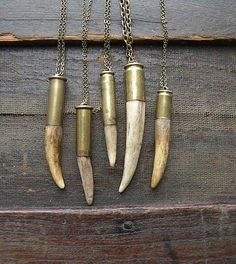 four necklaces with different types of horns hanging from chains on a wooden surface,