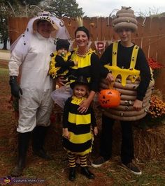 three adults and two children dressed up in bee costumes, standing next to each other