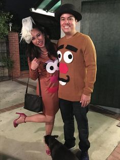 a man and woman in costumes pose for a photo with a dog on the sidewalk